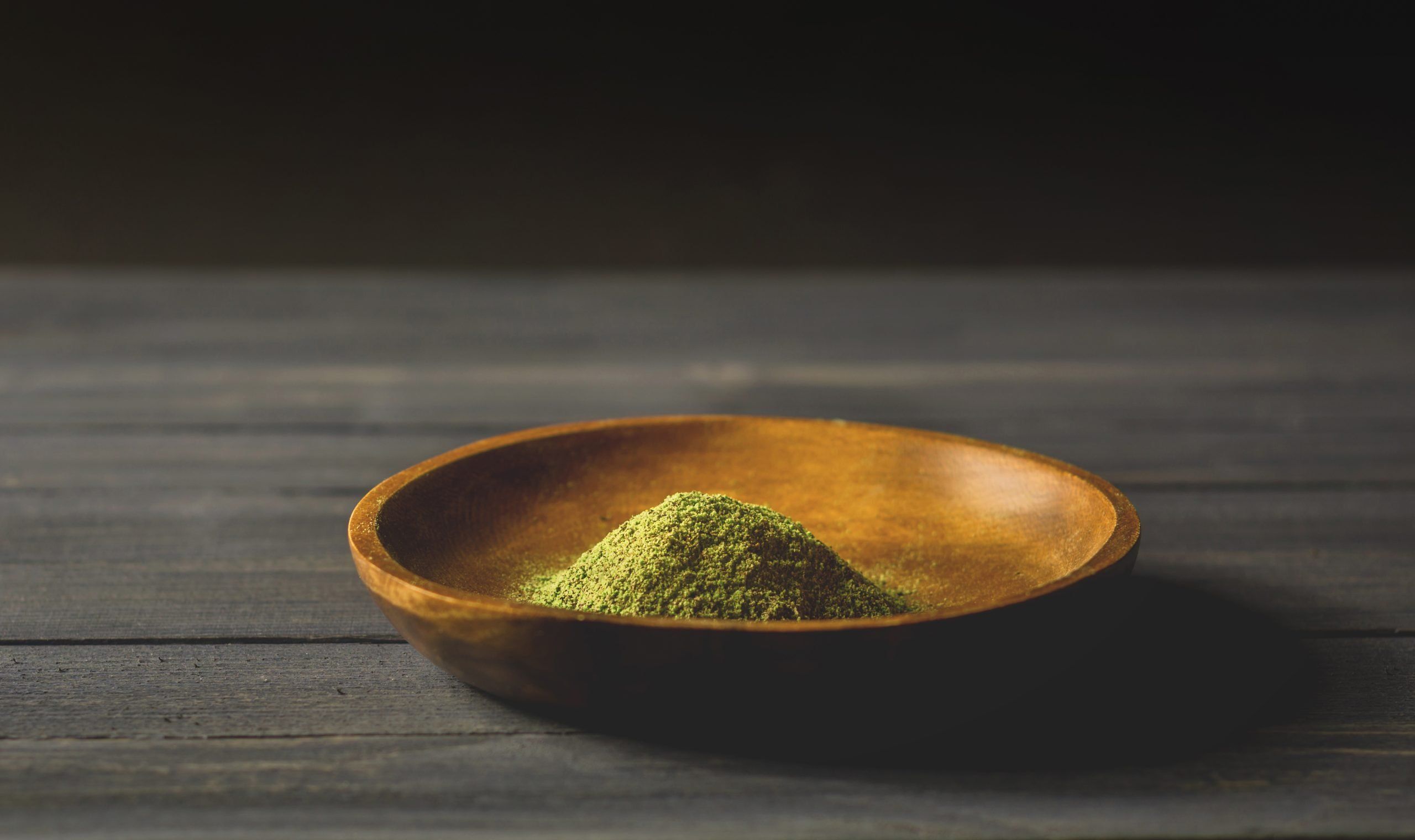 Mitragynina speciosa or Kratom powder in wooden bowl on table