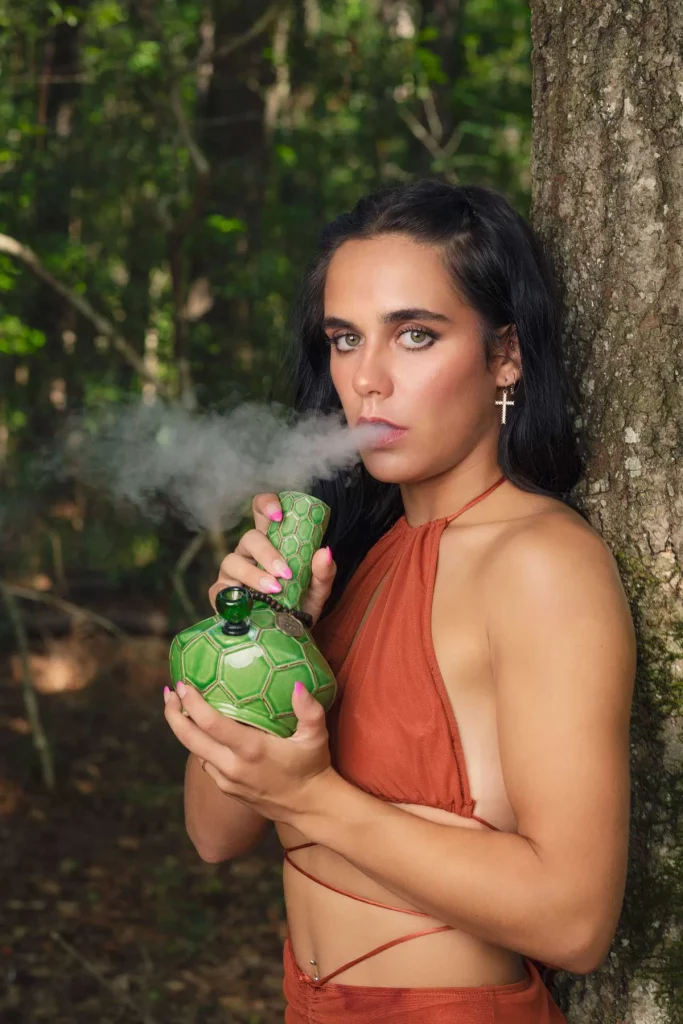 A person using a ceramic bong in an artistic indoor setting.
